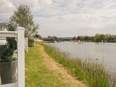 A lakeside view with grass and trees at Swan Haven in Grange-Over-Sands