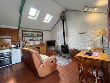 A living room with a sofa, table, and stove at Starling Cottage near Cowbridge