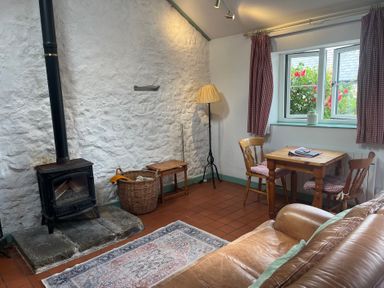 A living room with a stove, basket, and table at Starling Cottage near Cowbridge