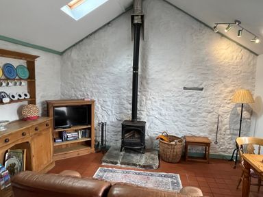 A snug with a wood-burning stove and television at Starling Cottage near Cowbridge