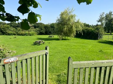 A garden with a gate and picnic tables at Starling Cottage near Cowbridge