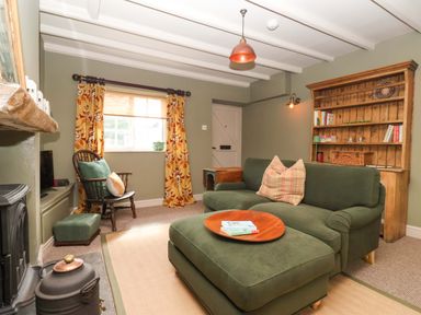 A living room with a sofa and bookshelf at The Cook’s Cottage in Malton