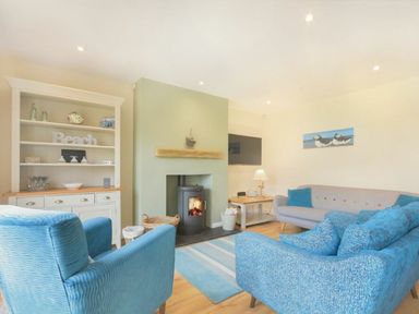 A living room with a fireplace and seating area at Beach Walk in Chathill