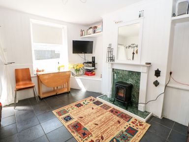 A living room with a fireplace a TV a wooden chair and a drop leaf table at Bridge Cottage Haltwhistle near Hadrians Wall