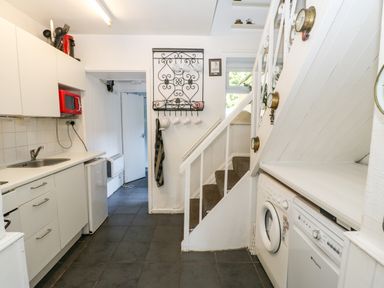 A kitchen with white cabinets and appliances including a washing machine dishwasher and red microwave at Bridge Cottage in Haltwhistle near Hadrians Wall