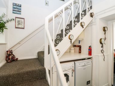 A staircase with a washing machine and dryer underneath at Bridge Cottage in Haltwhistle near Hadrians Wall