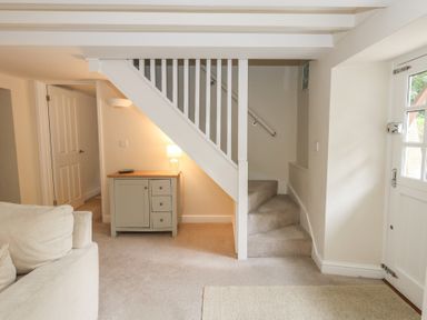 A hallway with stairs and a console table at Woodbine Cottage in Weymouth