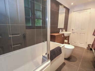 A bathroom with a bathtub and sink at Woodbine Cottage in Weymouth