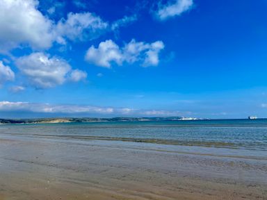 A beach with water and clouds at Woodbine Cottage in Osmington