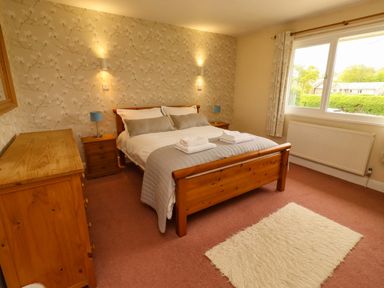 A bedroom with a bed and dresser at Campden in Rennington near Embleton