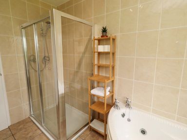 A bathroom with a shower and bathtub at Campden in Rennington near Embleton