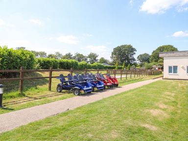 An outdoor area with go-karts parked along a pathway at Forest Retreat - FO26 Saxmundham
