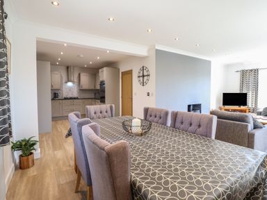 A dining room with a table and chairs adjacent to a kitchen at Tyn Y Weirglodd in Deiniolen