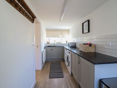 A utility room with a washing machine and microwave at Tyn Y Weirglodd in Deiniolen