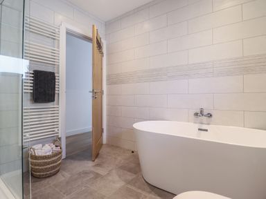 A bathroom with a bathtub and towel radiator at Tyn Y Weirglodd in Deiniolen