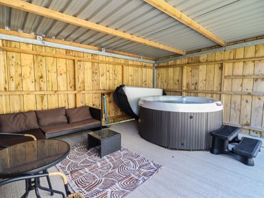 An outdoor area with a hot tub and seating at Tyn Y Weirglodd in Deiniolen