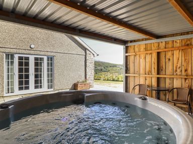 A hot tub with a sliding door and seating area at Tyn Y Weirglodd in Deiniolen