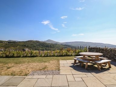 A garden with a picnic table and benches at Tyn Y Weirglodd in Deiniolen