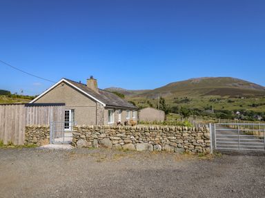 A house with a stone wall and a gate at Tyn Y Weirglodd in Deiniolen