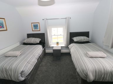 A bedroom with two beds and a window at Newgale Cottage in Newgale