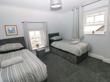 A bedroom with two beds and a window at Newgale Cottage in Newgale