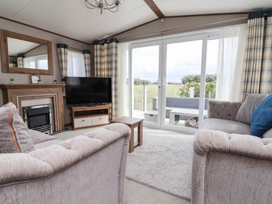 A living room with a television and fireplace at Caravan i35 Towyn