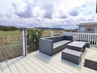 An outdoor sitting area with a sofa and coffee table at Caravan i35 in Towyn