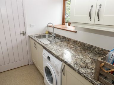 A laundry room with a washing machine and kitchen sink at The Gallops in Barry