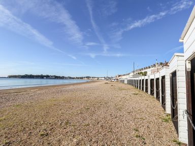 A beach with pebbles and beach huts at No 3 By The Sea in Weymouth
