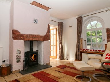 A living room with a fireplace and a window at Gorway Cottage in Teignmouth