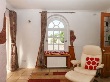 A sitting room with a chair and window at Gorway Cottage in Teignmouth