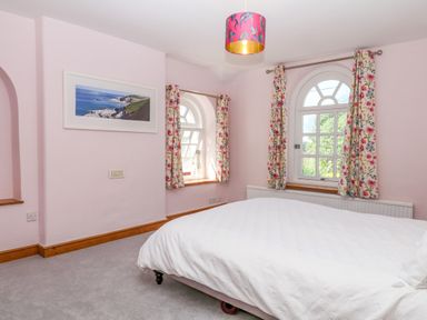 A bedroom with a bed and windows at Gorway Cottage in Teignmouth