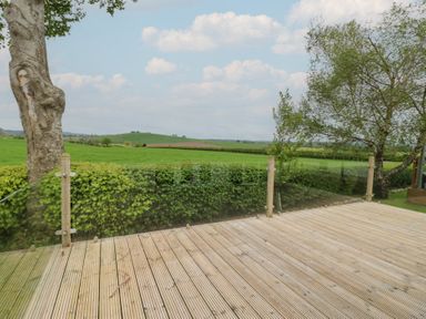 An outdoor view from a deck overlooking fields and trees at Plot 34 Carlisle