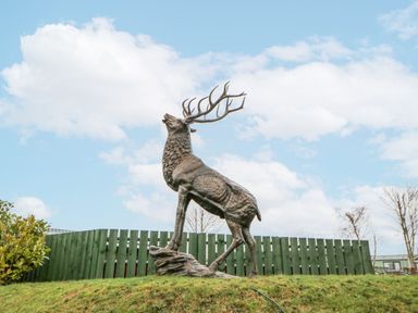 A deer statue on grass with a fence in the background at Plot 34 Carlisle