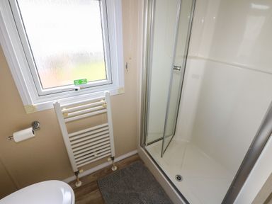 A bathroom with a shower, toilet, and towel rail at Plot 34 near Armathwaite