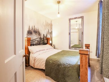 A bedroom with a bed and mirror at Hafanedd in Betws-y-Coed
