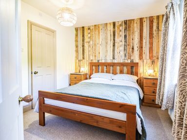 A bedroom with a bed and wooden wall at Hafanedd in Betws-y-Coed