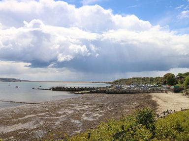 A view of the shoreline with a pier and boats at Little Gem in Weymouth