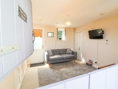 A living room with a sofa and television at Coach House Highampton near Black Torrington