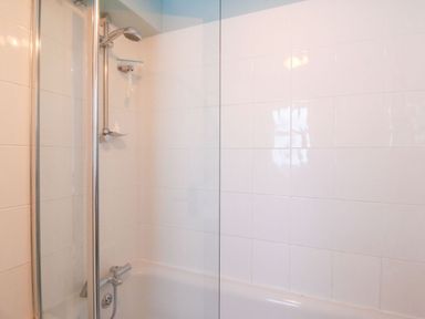 A shower with bathtub in a bathroom at Pixie Cottage in Weymouth