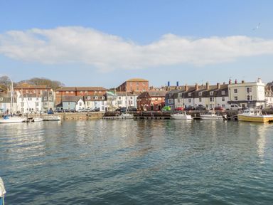 A waterfront view with buildings and boats at Pixie Cottage in Weymouth