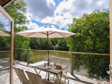 An outdoor seating area with table and chairs near a river at 11 Water's Edge near Pelynt