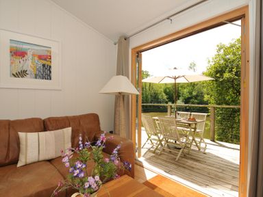 A living room with a sofa, lamp and door to a deck at 11 Water's Edge near Pelynt