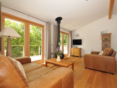A living room with a sofa, coffee table, and television at 11 Water's Edge near Pelynt