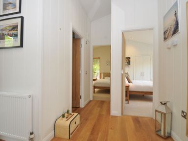 A hallway with paintings and a radiator at 11 Water's Edge near Pelynt