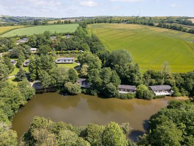An aerial view of houses by a water near Pelynt at 11 Water's Edge