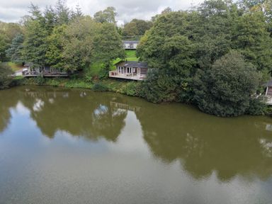 A view of cabins by a lake at 11 Water's Edge in Lanreath