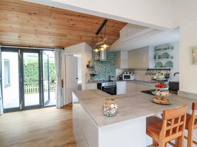 A kitchen with a counter and bar stools at Dingle Dell in Braunton