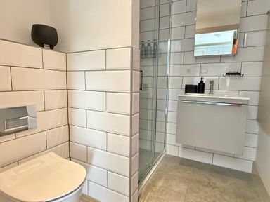 A bathroom with a toilet, shower, and sink at Charming Barn Annex with Stables New Forest Escape
