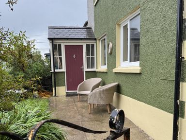 A house exterior with outdoor chairs and a front door at Llysawelon 2-Bed Cottage, Sleeps 5, Pets Ok near Llansteffan